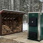 A modern outdoor wood boiler in a snowy rural yard
