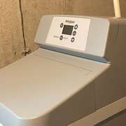 A traditional salt-based water softener with its main resin tank © Ecohome
