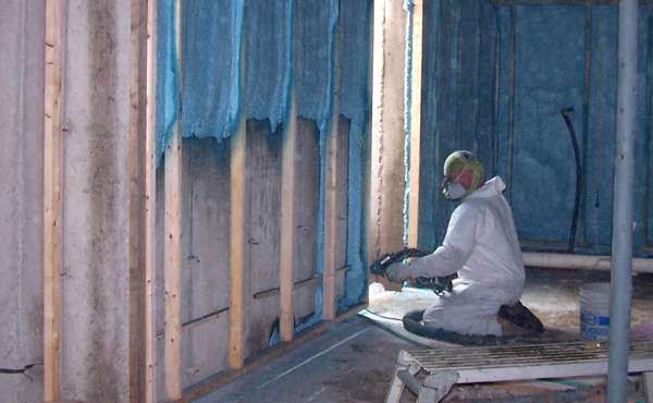 Closed cell spray foam insulation being applied to basement walls