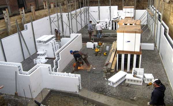 Workers assemble ICF blocks to pour a basement foundation