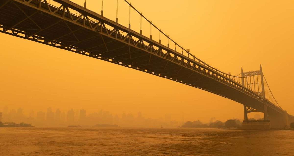 A hazy New York, New York, skyline & bridge colored by orange wildfire smoke