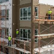 Workers installing a smooth, textured finish of an EIFS exterior on a building