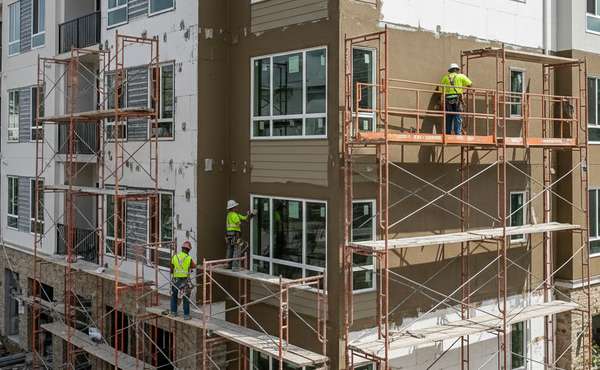 Workers installing a smooth, textured finish of an EIFS exterior on a building