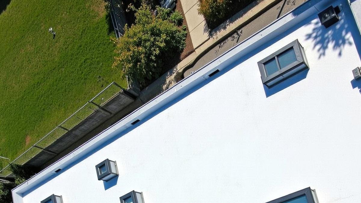 A clean, white TPO flat roof on a modern home with clear drainage paths.