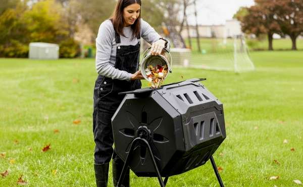 dropping food scraps in to a backyard compost tumbler