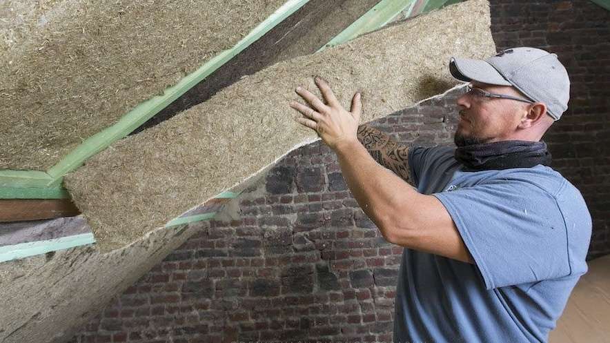 A worker installs natural non toxic insulation batt made from grass