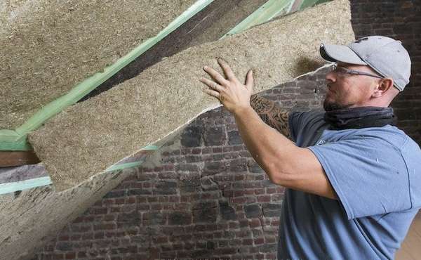 A worker installs natural non toxic insulation batt made from grass