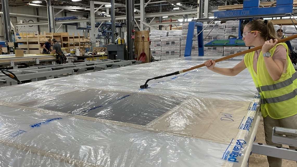Installing a smart vapor barrier on a prefab wall under construction.