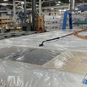 Installing a smart vapor barrier on a prefab wall under construction.