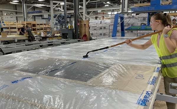 Installing a smart vapor barrier on a prefab wall under construction.