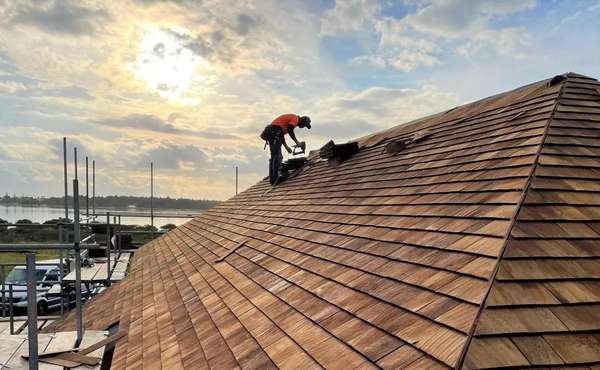 A classic home with a pitched roof and siding made of warm-toned cedar shingles.