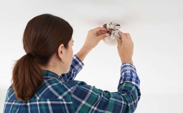 A woman connecting the battery of a carbon monoxide detector