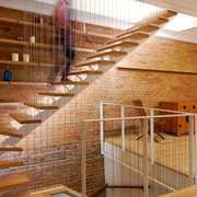A modern, minimalist staircase with wood treads Image © Studio MMA Architects