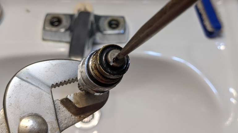 Flick the washer out of the faucet cartridge with the screw as you remove it