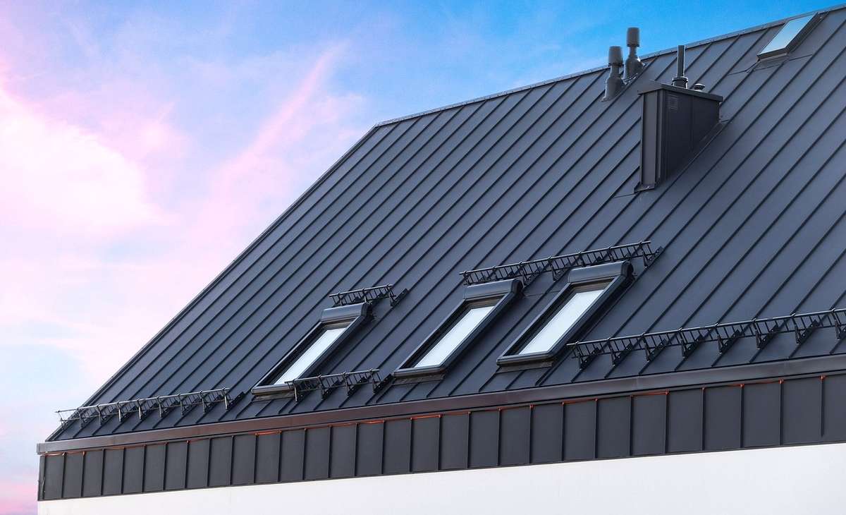 Un puits de lumière correctement installé avec des solins sur un toit métallique à joints debout, avec des canaux d'eau propres autour.