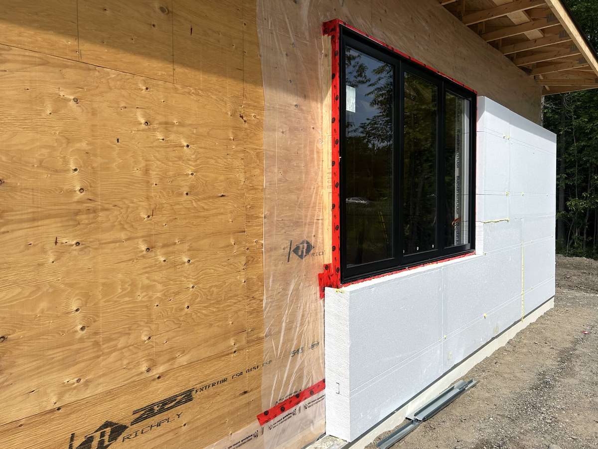 Installation de panneaux d'isolant rigide épais sur les murs extérieurs d'une nouvelle maison.