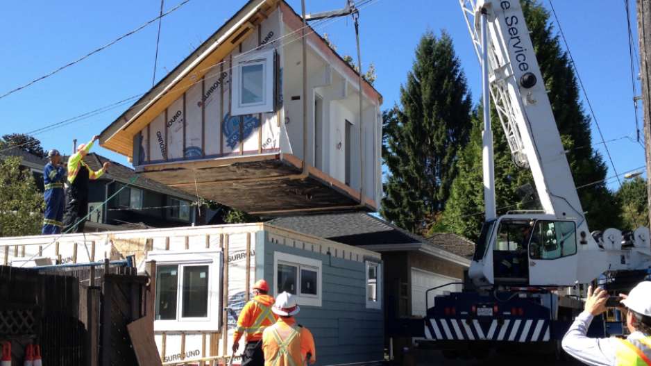 Une grue abaisse une section préfabriquée en place pour une nouvelle maison de ruelle.