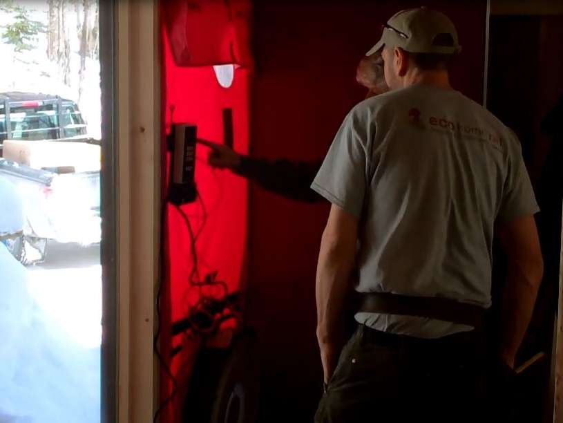 A blower door fan installed in the front door of an older brick home.