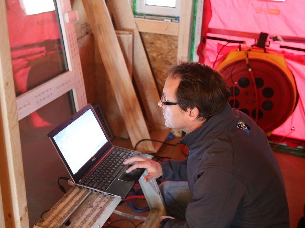 A worker measures air leakage in a home by conducting a blower door test