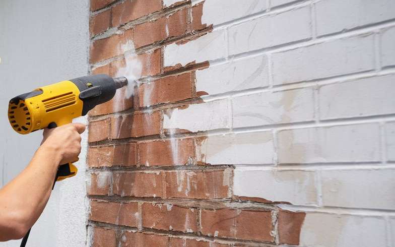 Heat gun being used to remove paint from bricks
