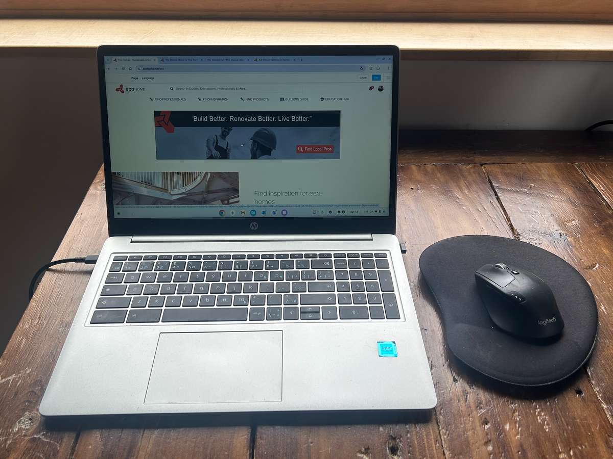 A laptop charging on a hard wooden desk rather than a bed or sofa.