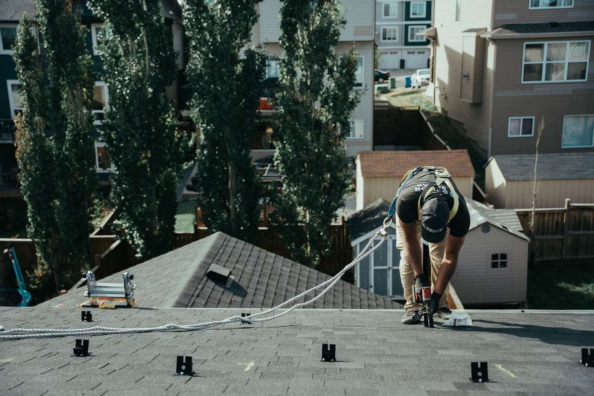 A worker installing solar panel mounts on a roof in Alberta