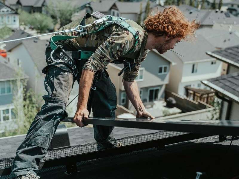 a worker installs solar panels on a roof in Alberta